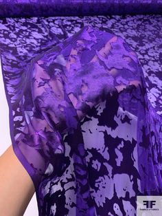 a woman's hand is holding up a purple dress with floral print on it