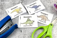 four dinosaur cards and scissors on a table