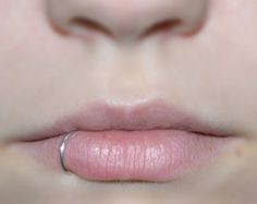 a close up view of a woman's lips with a ring on her lip