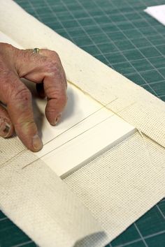 a person is making a piece of fabric with their hands on the edge of it