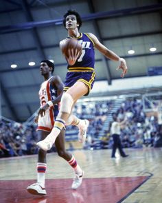 a basketball player is in mid air after going to the basket during a game with an opposing team