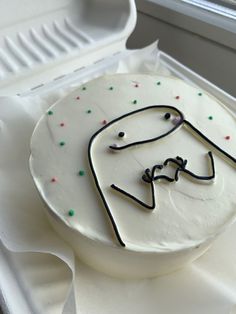 a white cake with black icing and a man's face on it in a box