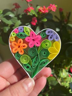 a hand holding a heart shaped paper decoration