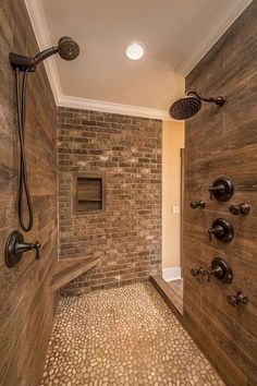 a walk in shower sitting inside of a bathroom next to a brick wall and tiled floor