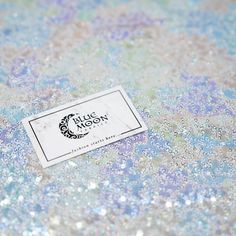 a white business card sitting on top of a blue and silver glittered table cloth