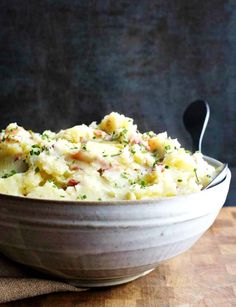 a bowl filled with mashed potatoes on top of a wooden table