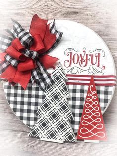 a white plate topped with christmas decorations on top of a wooden table next to a red ribbon