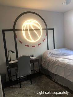 a room with a bed, desk and chair in it that has a neon ball on the wall