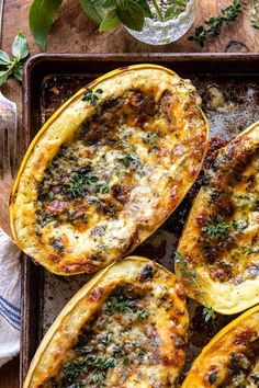 baked stuffed acorns on a baking sheet with herbs and seasoning sprigs