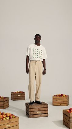 a man standing on top of wooden crates filled with apples and wearing a white t - shirt