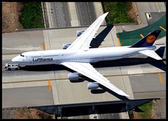 an airplane that is flying in the sky above some buildings and roads, with it's landing gear down