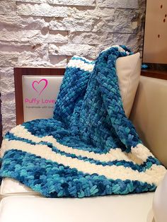 a blue and white crocheted blanket sitting on top of a toilet next to a pillow