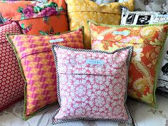 many colorful pillows are stacked on top of each other in different colors and patterns,