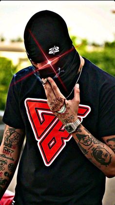 a man wearing a black t - shirt with red letters on the chest and hands covering his face