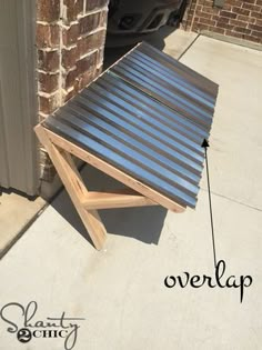 a metal table sitting on top of a sidewalk next to a brick building with the word overlap written below it