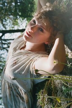 a beautiful young woman leaning against a tree