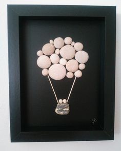 a black frame with some white rocks in the shape of a balloon on it's side