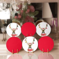 four red and white plates with deer head on them, sitting on a table in front of a christmas tree