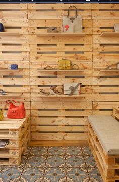 the inside of a store with wooden pallets on the wall and shelves filled with purses