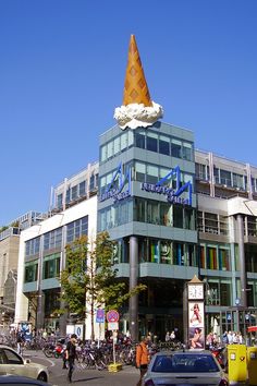 an ice cream cone on top of a building in the middle of a busy street