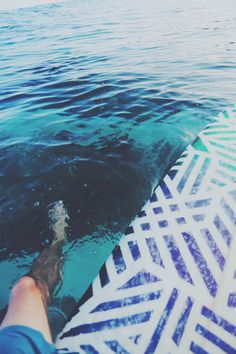 a person standing on a surfboard in the water with their feet propped up against the board