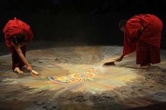 two men in red robes are painting on the ground