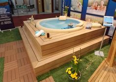 a hot tub sitting on top of a lush green field next to a wooden deck