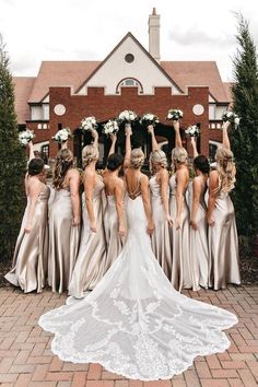 a bride and her bridal party standing in front of a house with their hands up