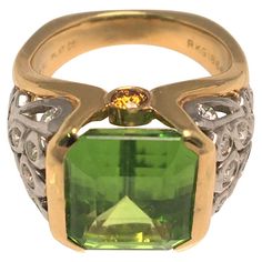 By designer Richard Krementz, known for high quality and exceptional stones. This ring is an attention grabber! It's beautiful green colored Peridot is complemented by a platinum, 18K yellow gold and diamond design/mounting. Emerald cut peridot in partial bezel setting- approximately 11.7mm X 11.0mm 26 round diamonds in various sizes - approximately .74tdw 2 round orange (sapphires) on each side Stamped "750", "PLAT", "RKG" and "1866" Approximate size is 5.5 (can be sized) 7.3dwt Luxury Lime Green Ring, Luxury Lime Green Jewelry With Accent Stones, Luxury Unique Peridot Rings, Attention Grabber, Yellow Ring, Yellow Rings, Orange Sapphire, Jewelry Fashion Trends, Diamond Design