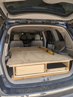 the back end of a car with an open hatchback door and wooden table in the trunk