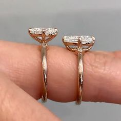 a woman's hand is holding two gold rings with diamonds on them and one has a diamond in the middle