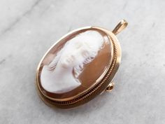 "The luster of the shell of this vintage cameo is absolutely gorgeous. Warm and soft, the tone and color of the lady's skin is very lifelike. Particularly nice on this brooch is the carving, with incredible details in the lady's hair. This pendant does not come with the chain shown. Please feel free to contact us, we will help you find the perfect chain for your style and budget! Metal: 14K Yellow Gold Gem: Shell Cameo Gem Measurements: 18.2 x 24.0 mm, Oval Measures: 22 x 34 mm, with bail Marks: Cameo Jewelry, Cameo Ring, Vintage Cameo, Cameo Brooch, Ancient Jewelry, Cameo Pendant, July Birthstone, Eternity Bands, Estate Jewelry