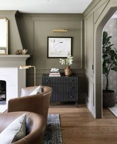 a living room filled with furniture and a fire place under a mirror on the wall