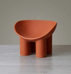 an orange bowl sitting on top of a wooden table next to a white wall and floor