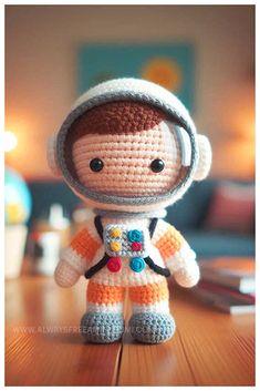 a crocheted toy that looks like an astronaut is standing on a wooden table