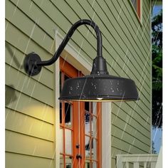 an outdoor light on the side of a house with rain coming from it's roof