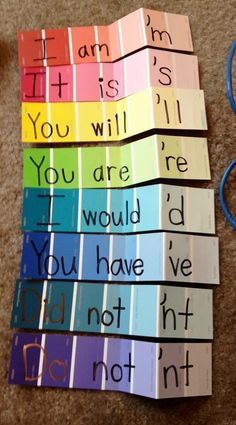 rainbow cards with words written on them sitting on the floor next to scissors and yarn