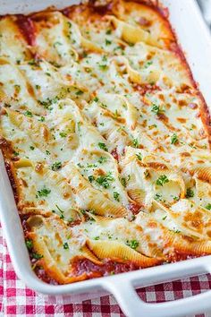 a square casserole dish filled with cheese and pasta sauce, garnished with parsley