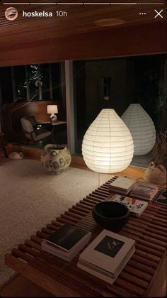 a living room filled with lots of furniture next to a large glass window covered in paper lanterns