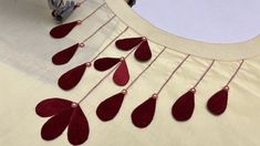 a close up of a piece of cloth with red thread and beads hanging from it