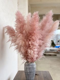 a vase filled with pink feathers on top of a wooden table