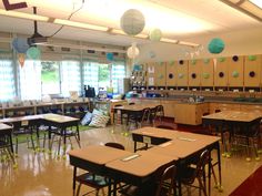 an empty classroom with desks and chairs in the middle, decorated with paper lanterns hanging from the ceiling