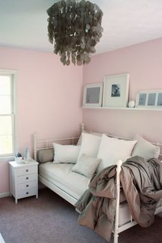 a bedroom with pink walls and a white couch in the corner, next to a window