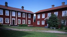 two large red buildings with white windows and some benches in front of them on the grass