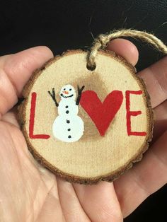 a hand holding a wooden ornament that says love with a snowman on it