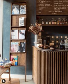 a coffee shop with wooden shelves filled with books and magazines on the wall next to a counter