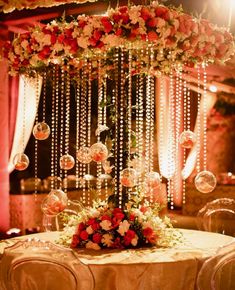 a table topped with lots of flowers and hanging bubbles on it's headboard