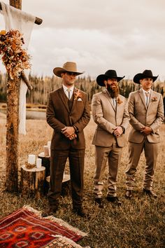 three men in suits and hats standing next to each other near a cross on the ground