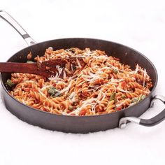 a skillet filled with pasta and cheese on top of a white table covered in snow