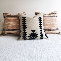 three decorative pillows on top of a bed